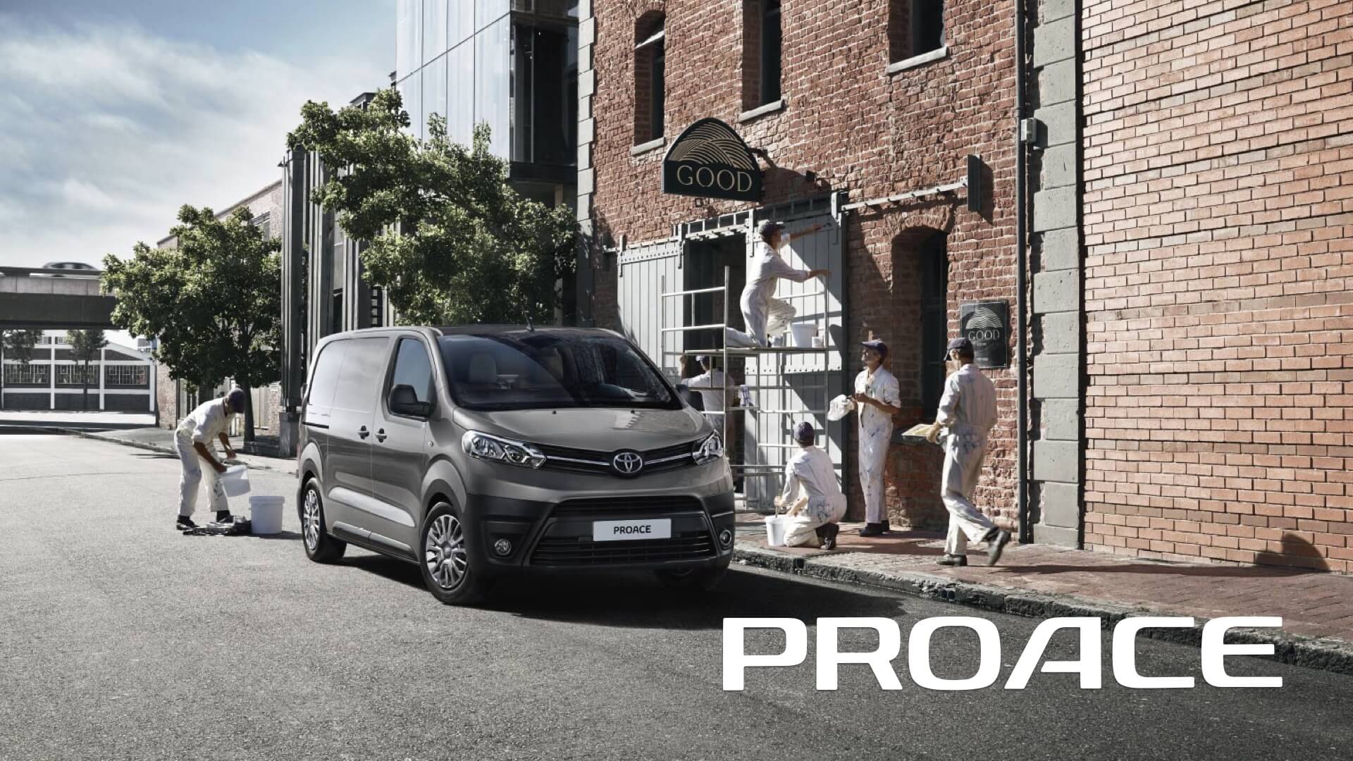 Vista frontal del Toyota Proace aparcado junto a un edificio mientras unos obreros descargan material del vehículo